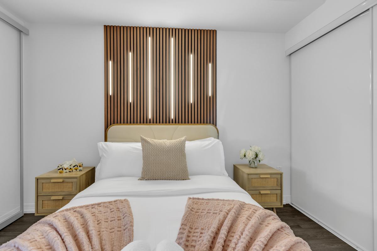 Bedroom with a slatted wood feature wall and backlit panels