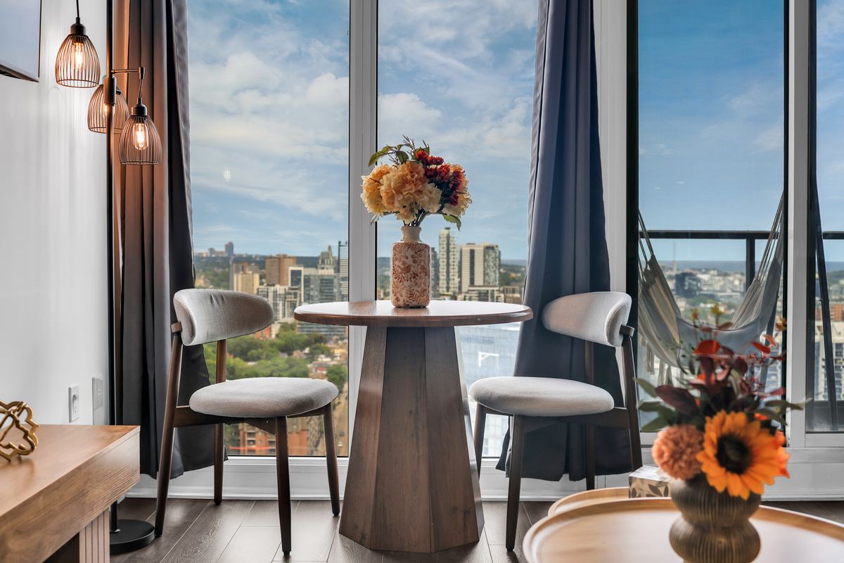 Dining table for two beside floor-to-ceiling windows over Toronto