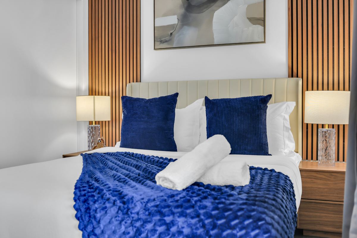 Made bed with fresh towels and a navy throw