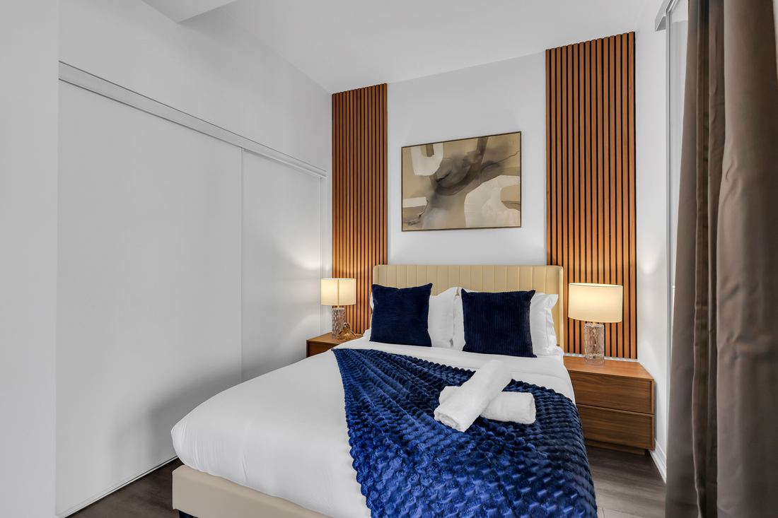 Bedroom with an upholstered headboard, slatted wood panels and bedside lamps